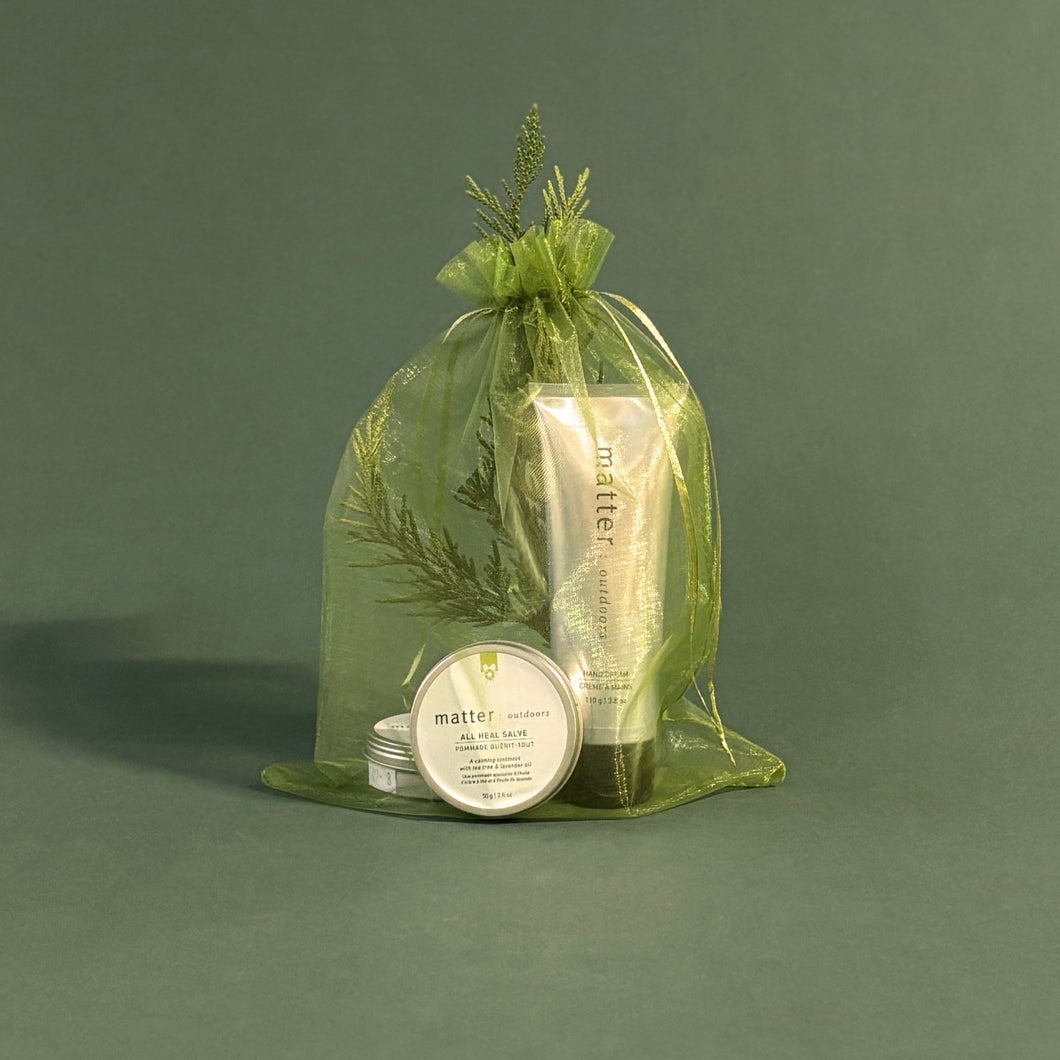 Set of skincare products in a green organza bag on a dark green background